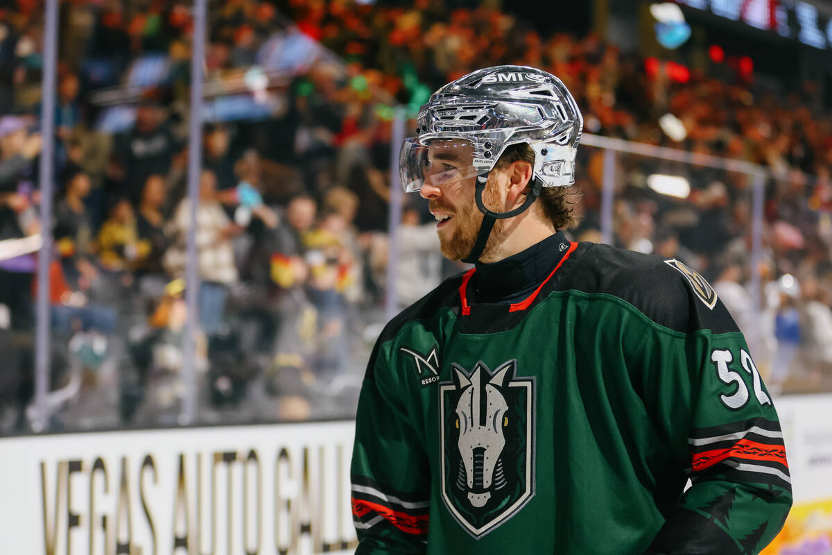 Silver Knights defenseman Dylan Coghlan interacts with a fan while shoveling piles of toys on t ...