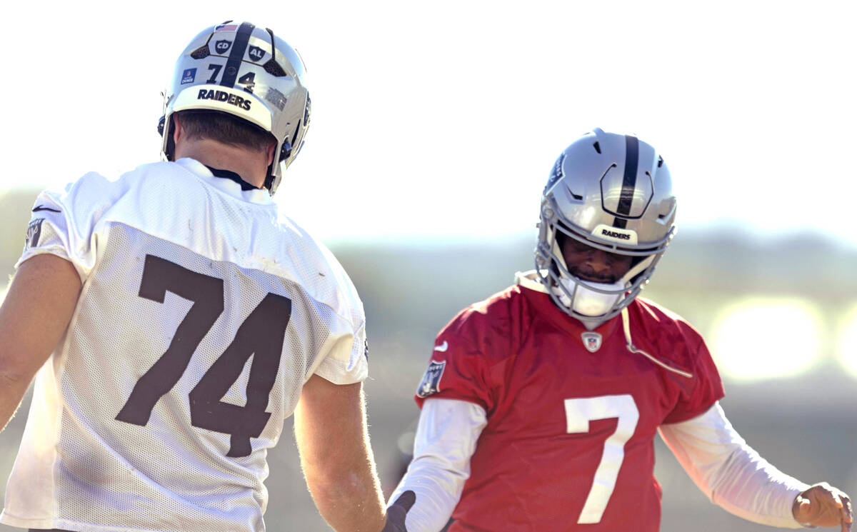 Raiders offensive tackle Kolton Miller (74) and quarterback Geno Smith (7) greet each other dur ...