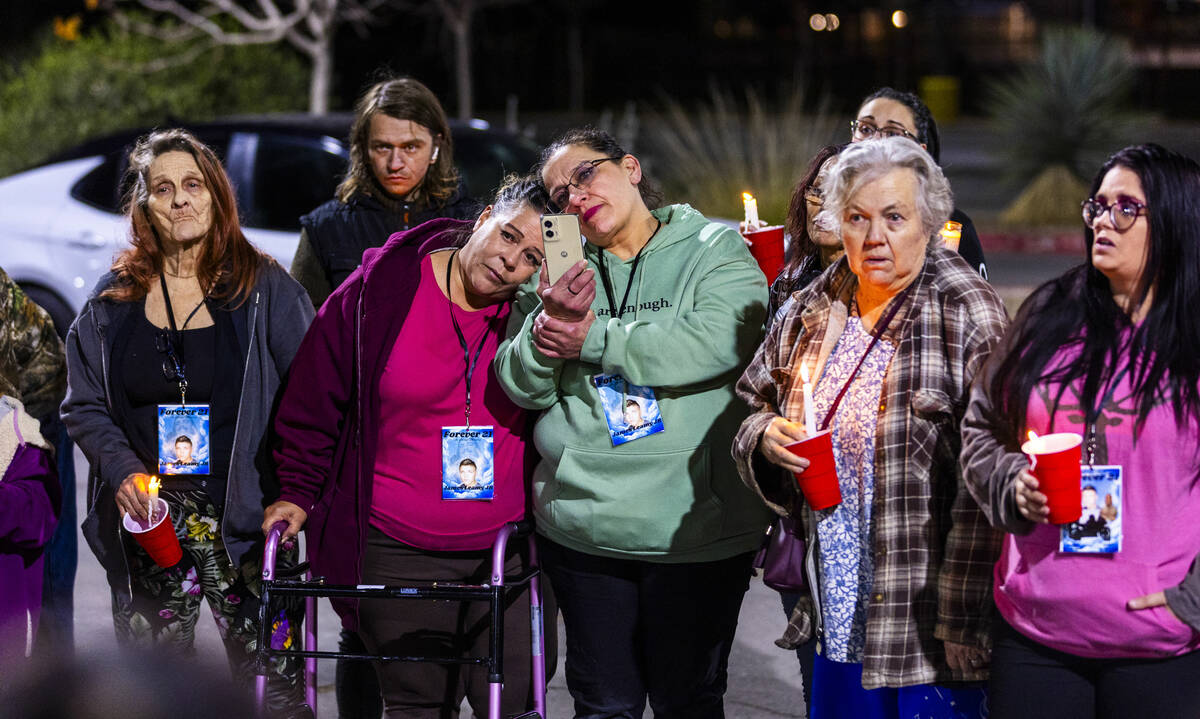 Renee Riley, center, is comforted by family and friends during a candlelight vigil for her son ...