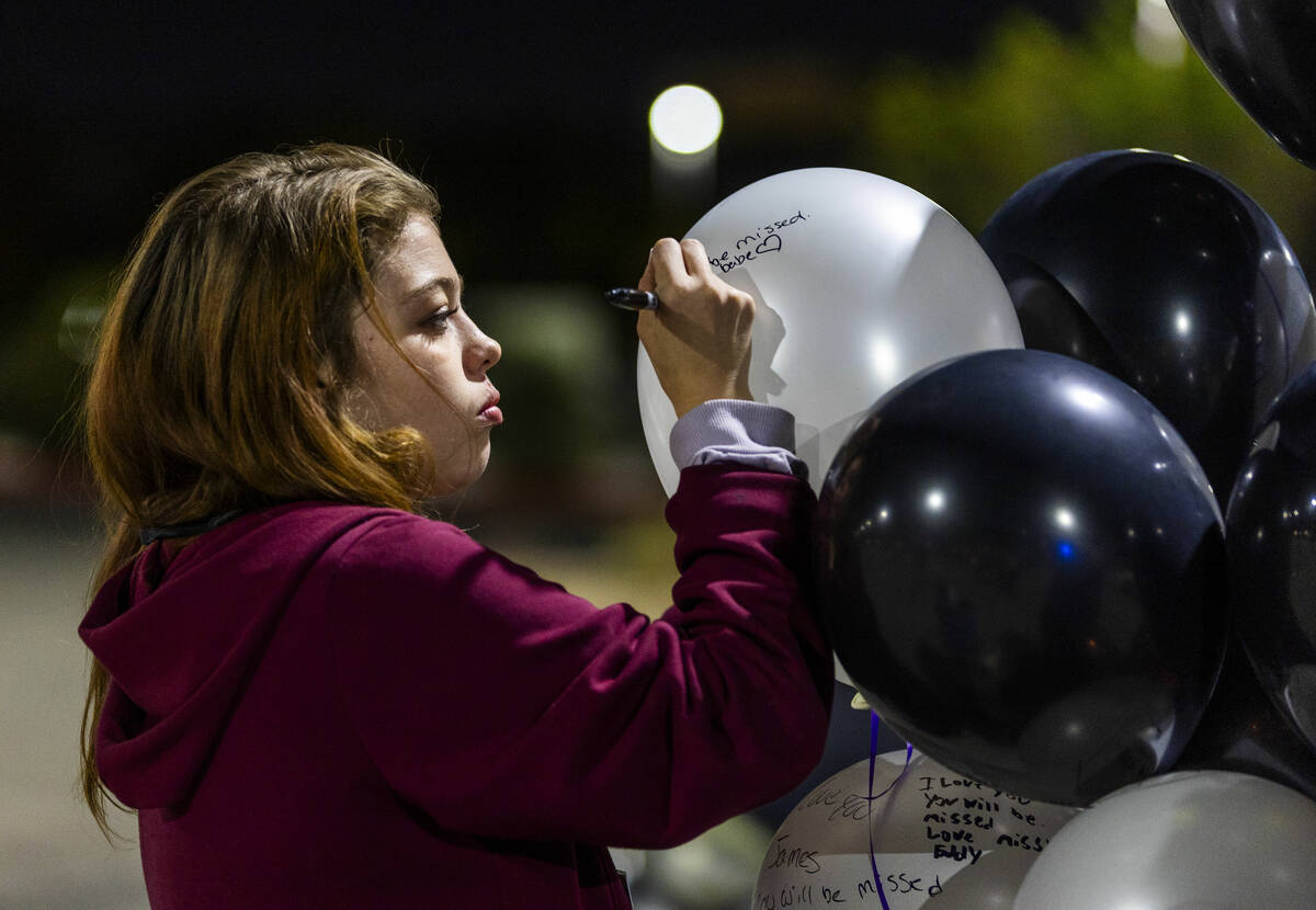 Girlfriend Alissa Rogers writes a message to James Leamy Jr., during a candlelight vigil for hi ...