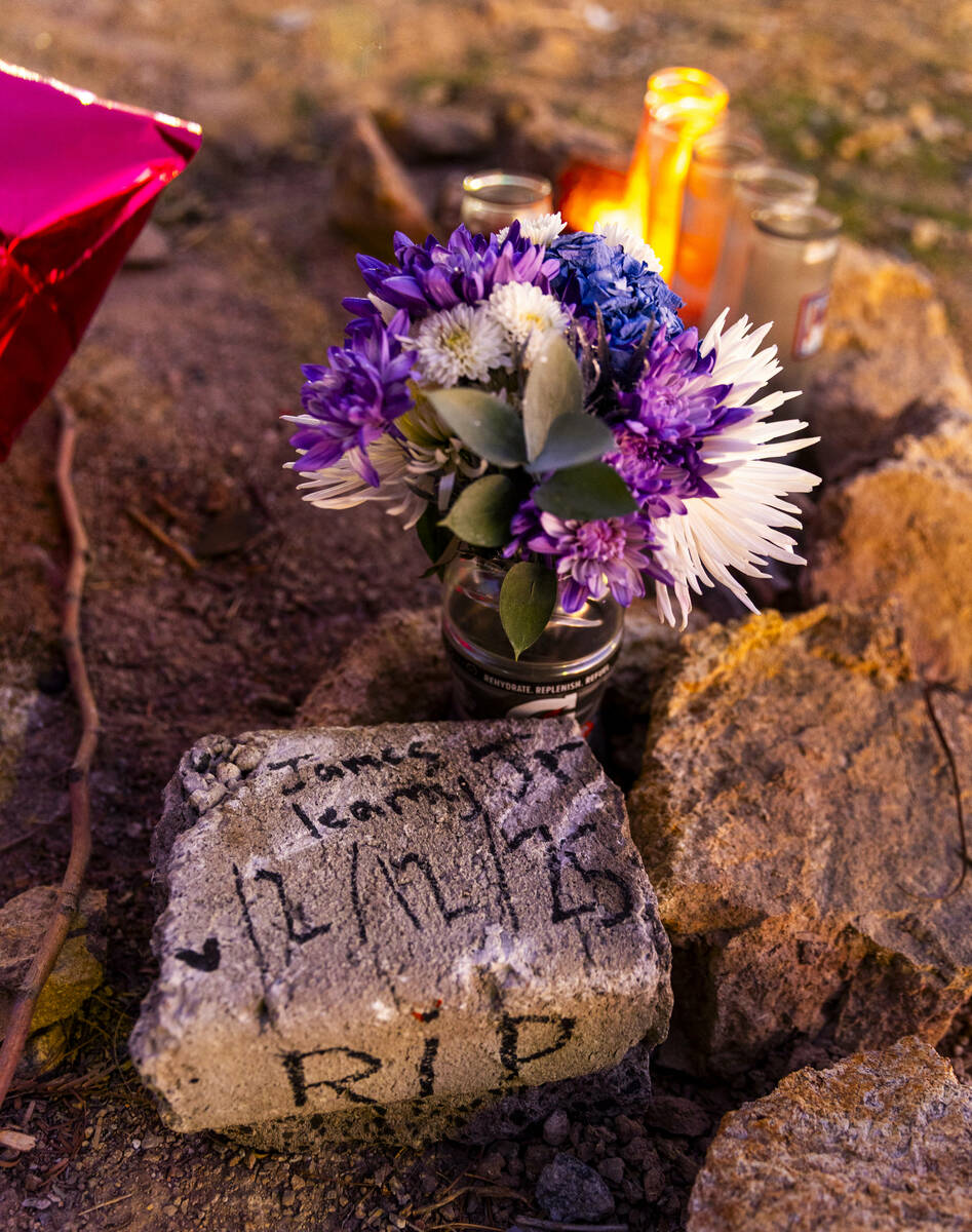 A stone marker, flowers and lit candles in remembrance of James Leamy Jr., during a vigil for h ...