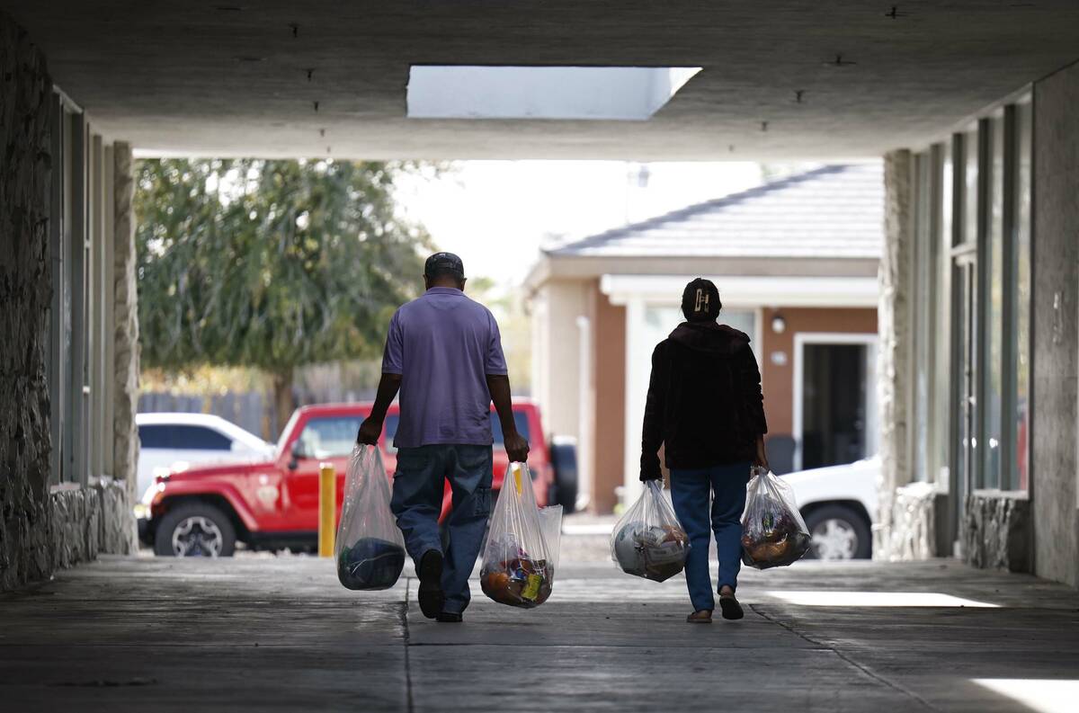 People walk bags of food to their car at The Just One Project food dispensary Thursday, Dec. 18 ...