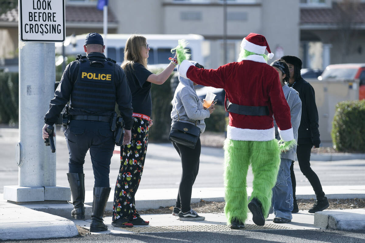 Clark County School District police officer Keith Habig high fives teens after using a crosswal ...