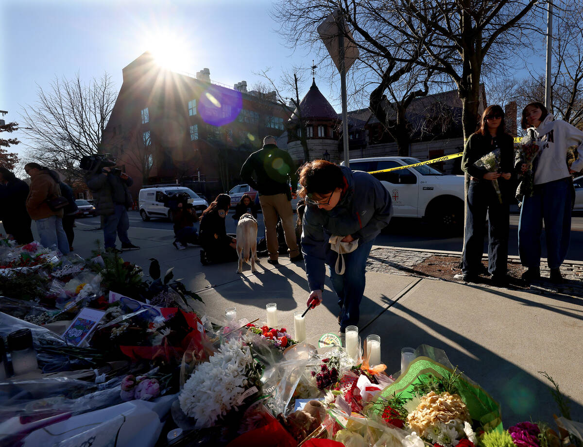 A woman lights a candle at a memorial set up in front of the Barus and Holley engineering build ...