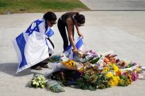 Women place flowers at a memorial outside Bondi Pavilion at Sydney's Bondi Beach, Monday, ...