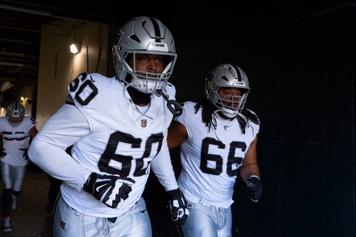 Las Vegas Raiders tackle Charles Grant, left, and guard Dylan Parham, right, head to the field ...