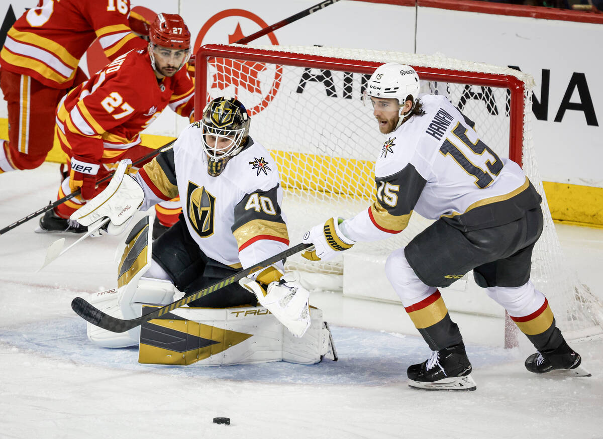 Vegas Golden Knights goalie Akira Schmid, center, and Noah Hanifin (15) reach for the puck as C ...