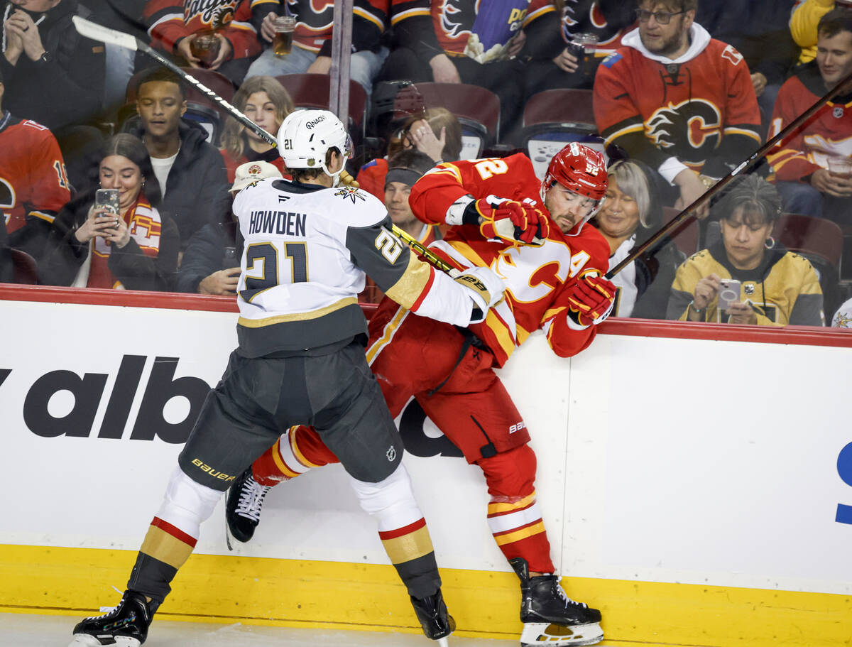 Vegas Golden Knights' Brett Howden, left, checks Calgary Flames' MacKenzie Weegar, ri ...