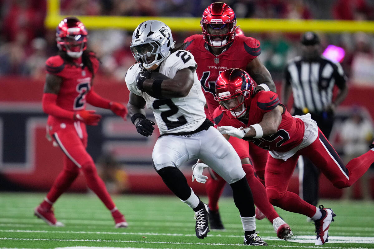 Las Vegas Raiders running back Ashton Jeanty, middle, runs past Houston Texans cornerback Myles ...