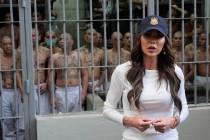 As prisoners stand looking out from a cell, Homeland Security Secretary Kristi Noem speaks duri ...