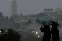 People carry umbrellas while walking on a path at Alamo Square Park, in San Francisco, Tuesday, ...