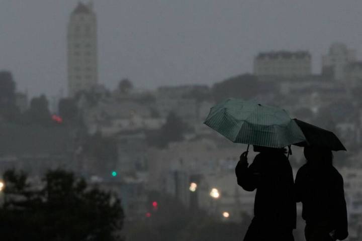 People carry umbrellas while walking on a path at Alamo Square Park, in San Francisco, Tuesday, ...