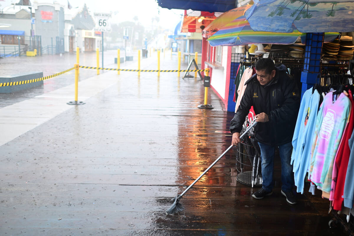 Miguel Lopez sweeps water from Marlene's Beachcomber on the Santa Monica pier Wednesd ...