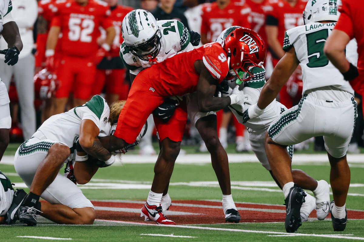 Hawaii defenders tackle UNLV running back Jai'Den Thomas (9) during the first half of the ...