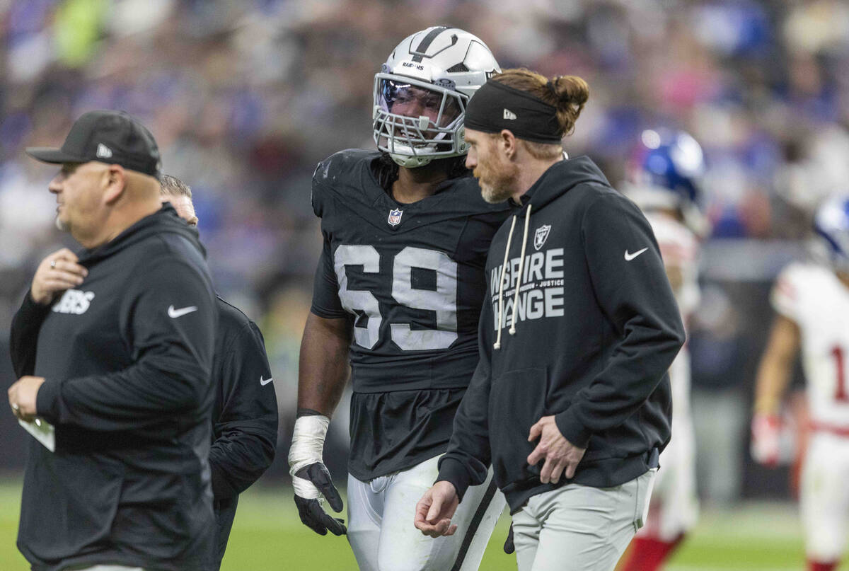 Raiders defensive tackle Adam Butler (69) is helped off of the field after sustaining an injury ...