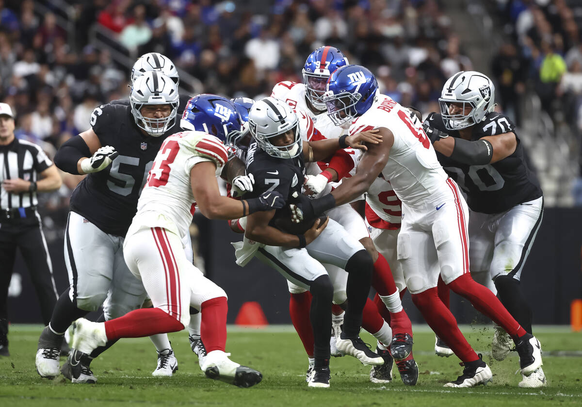 Raiders quarterback Geno Smith (7) gets sacked by a group of New York Giants defenders includin ...