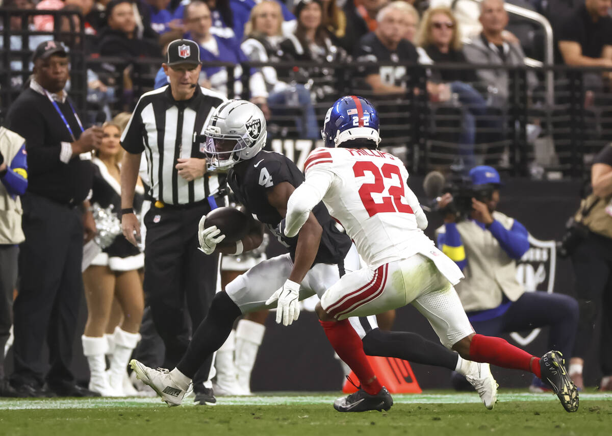 Raiders wide receiver Shedrick Jackson (4) runs the ball under pressure from New York Giants co ...