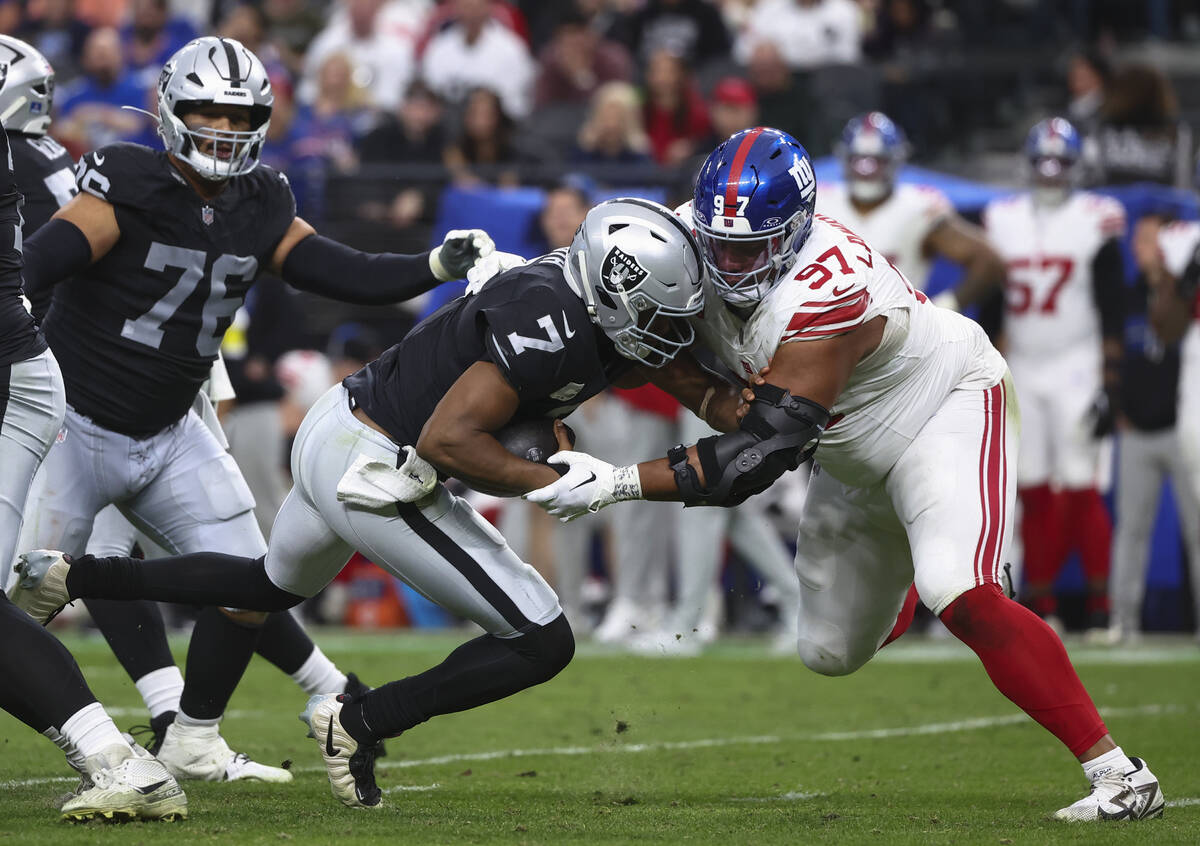 Raiders quarterback Geno Smith (7) gets sacked by New York Giants defensive tackle Dexter Lawre ...