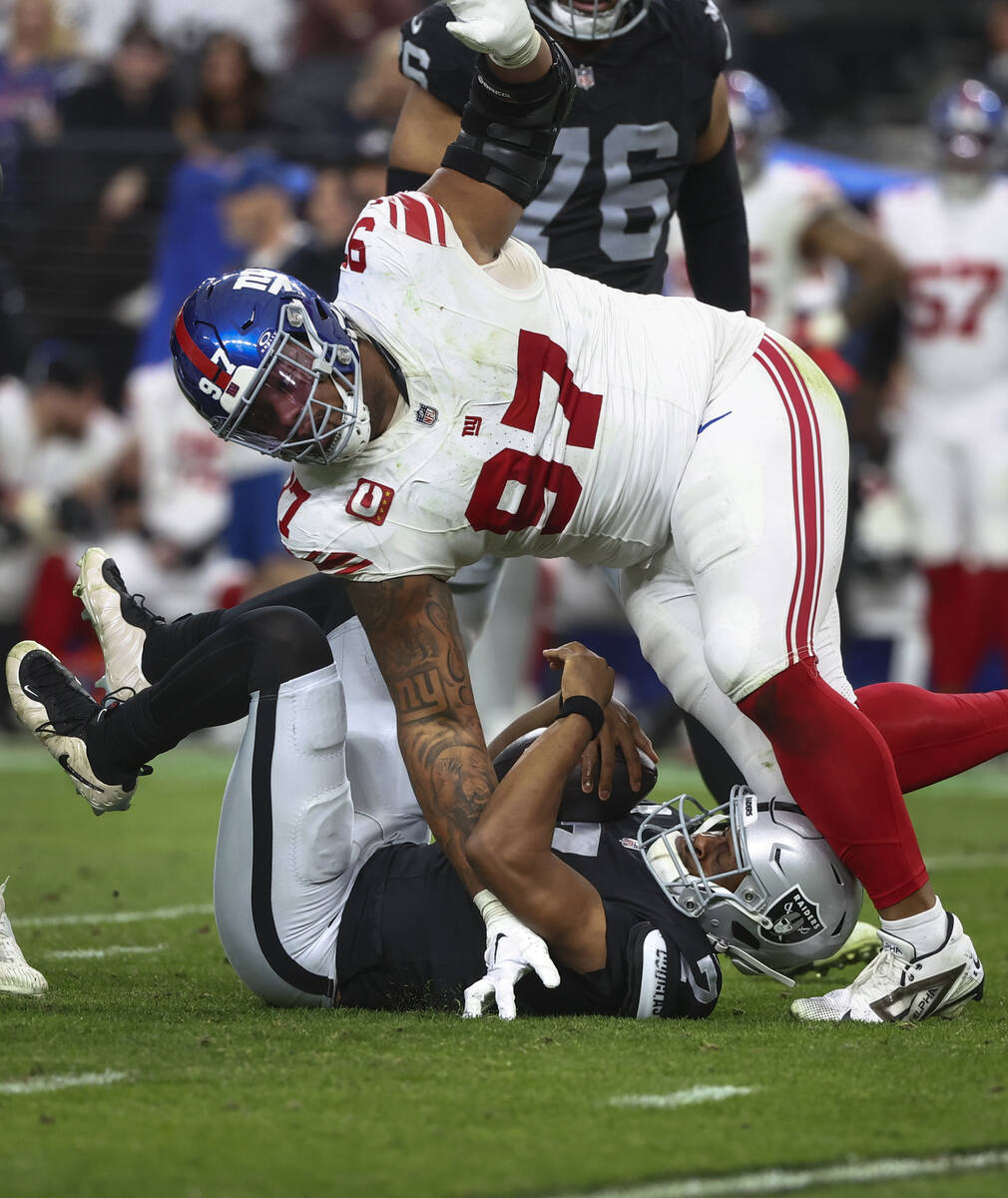 Raiders quarterback Geno Smith (7) gets sacked by New York Giants defensive tackle Dexter Lawre ...