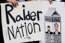 Fans hold signs with photographs of injured Raiders defensive end Maxx Crosby (98) and tight en ...