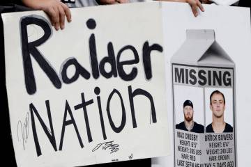 Fans hold signs with photographs of injured Raiders defensive end Maxx Crosby (98) and tight en ...