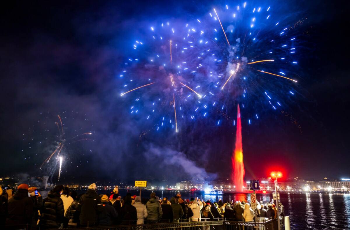 Fireworks illuminate the sky in bay of Geneva behind the famous water fountain "Le Jet d'Eau", ...