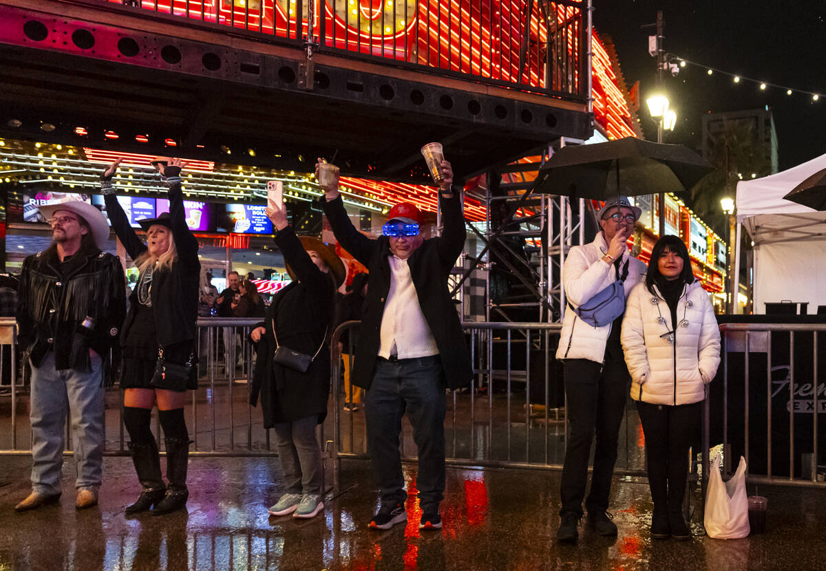 New Year's revelers dance to a DJ while trying to stay out of the rain at the Fremont Stre ...