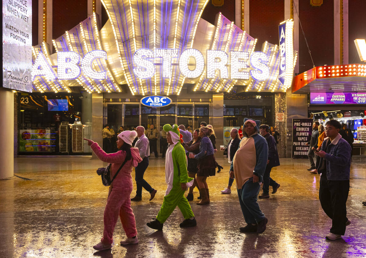 New Year's revelers wearing onesies walk around the Fremont Street Experience on Wednesday ...