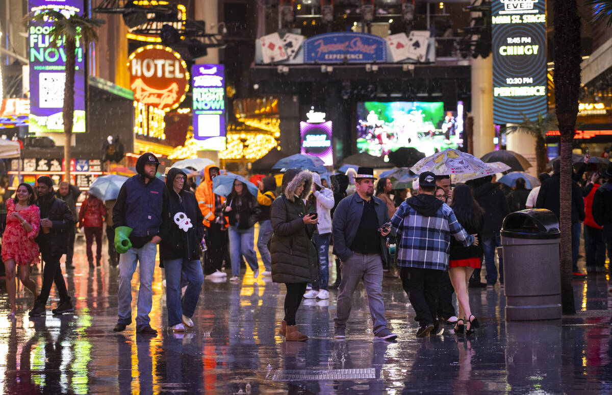 New Year's revelers walk through the rain at the Fremont Street Experience on Wednesday, D ...
