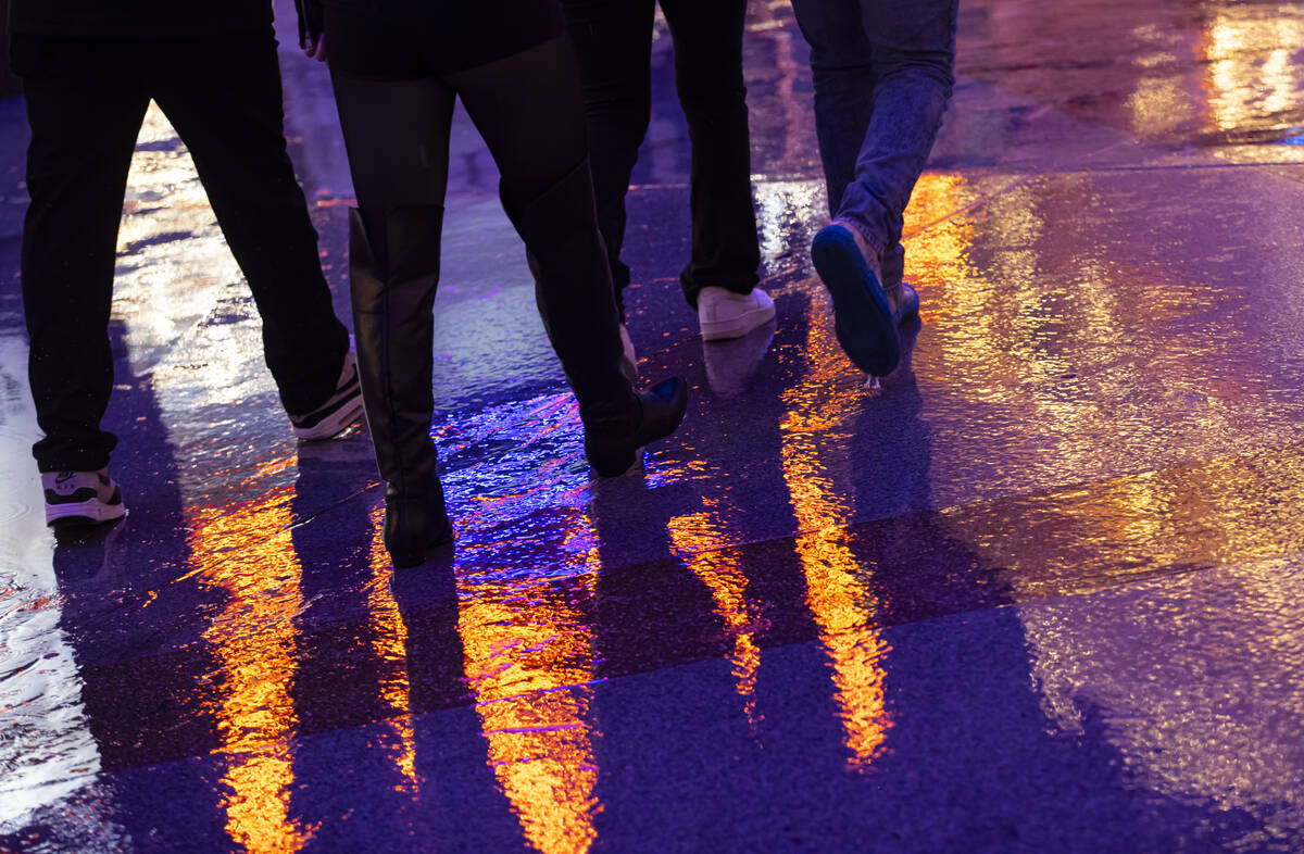 New Year's revelers walk in the rain at the Fremont Street Experience on Wednesday, Dec. 3 ...