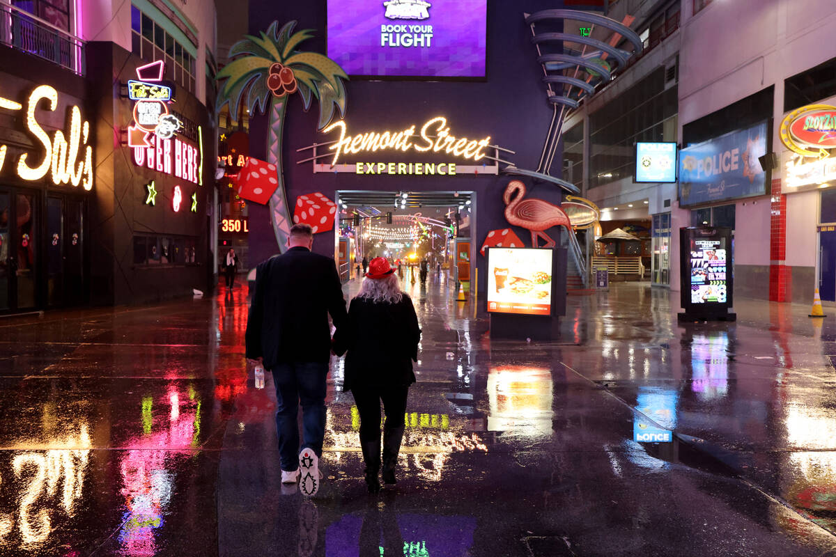 A couple who declined to give their names walk at the Fremont Street Experience in downtown Las ...