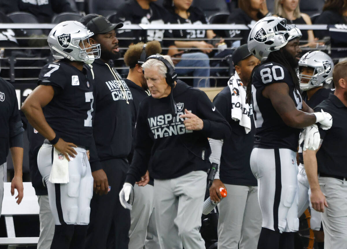 Raiders head coach Pete Carroll walks past quarterback Geno Smith, left, and tight end Ian Thom ...