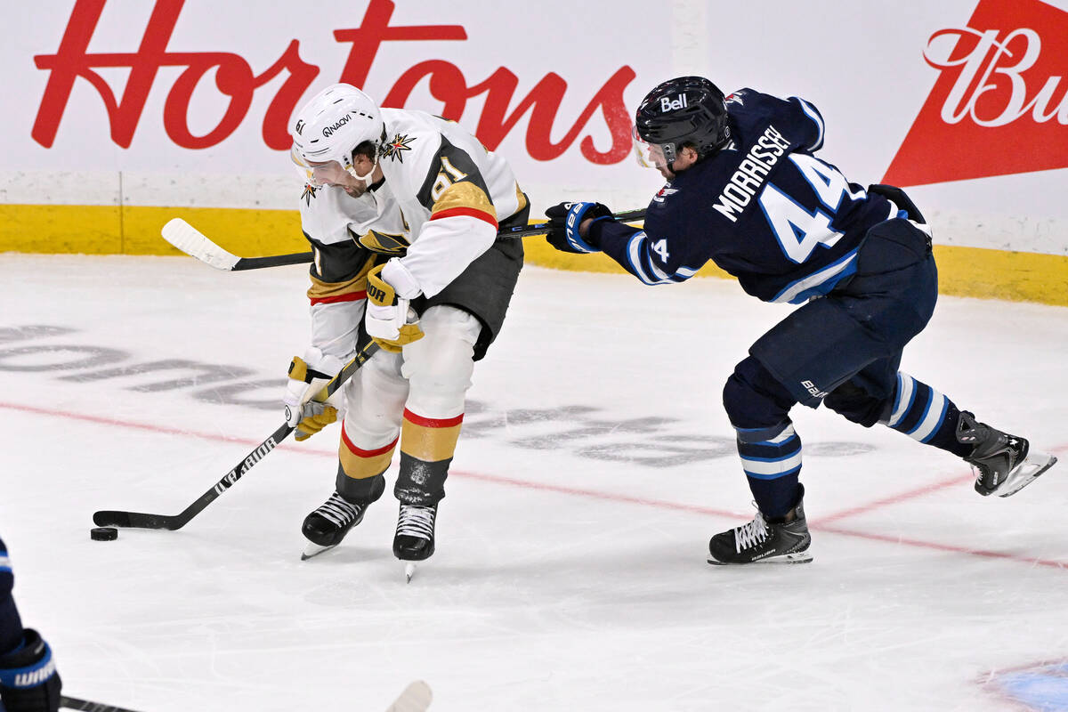 Vegas Golden Knights' Mark Stone (61) is hooked by Winnipeg Jets' Josh Morrissey (44) ...