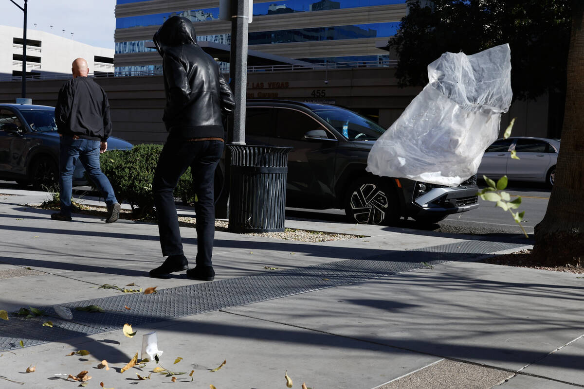 The wind blows a plastic bag and leaves as pedestrians walk along Third Street in Downtown Las ...