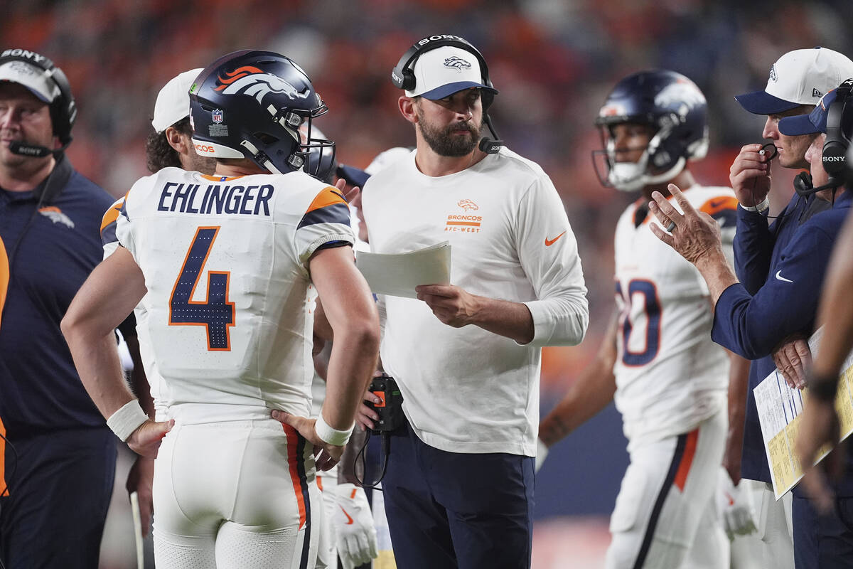 Denver Broncos quarterback Sam Ehlinger (4) confers with quarterbacks coach Davis Webb in the s ...