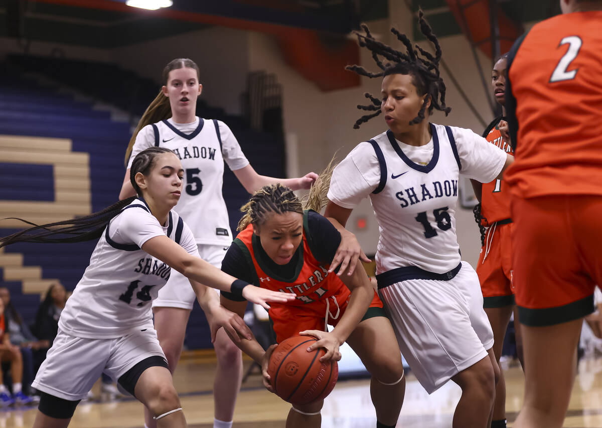 Mojave’s Armonney Wright (11) grabs a rebound between Shadow Ridge guard Chanel Gafeney ...