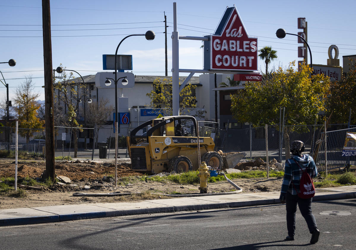 A woman crosses the street as a construction crew works to demolish the former Gables Motel, wh ...