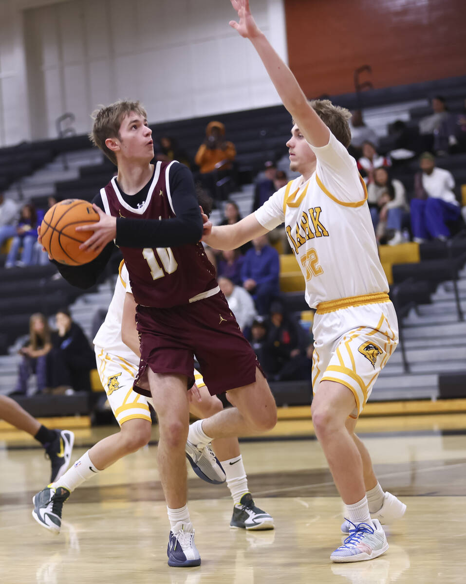 Faith Lutheran guard Jackson Klein (11) looks to shoot under pressure from Clark guard Hudson L ...