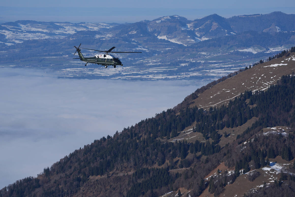 Marine One, carrying President Donald Trump, flies over snow covered mountains during his trans ...