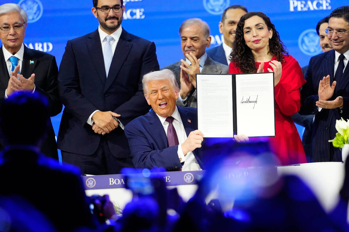 President Donald Trump holds the charter during a signing ceremony on his Board of Peace initia ...