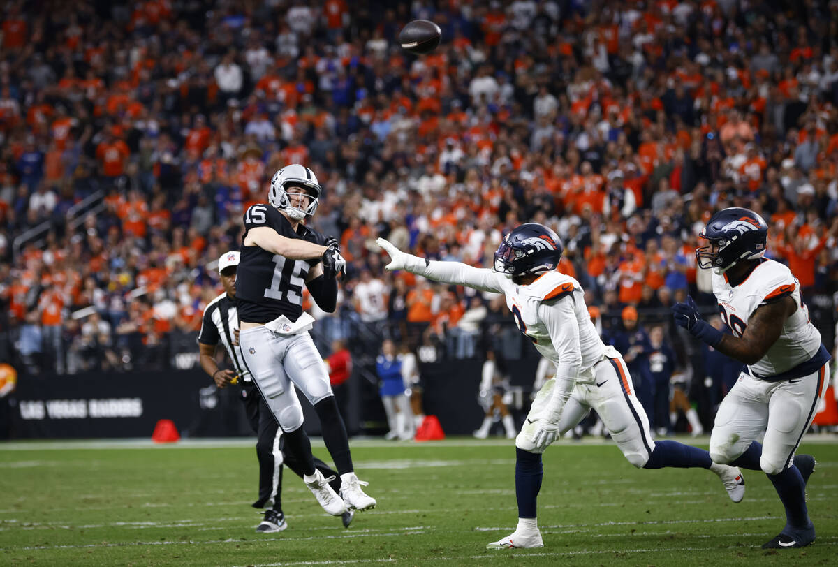 Raiders quarterback Kenny Pickett (15) throws a pass under pressure from Denver Broncos Jonatho ...