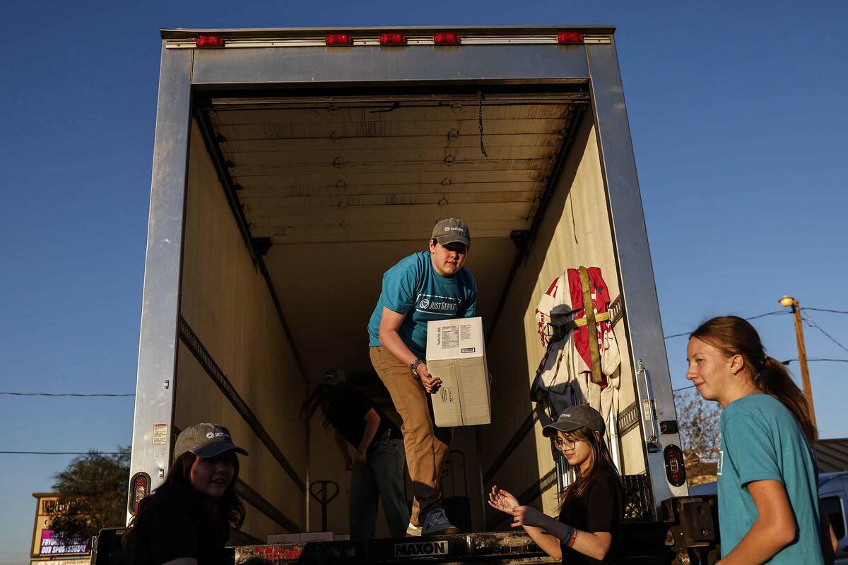 Student volunteers Preston Woodbury, top/left, Morgan Moncrief and Esther Burton unload a semi- ...