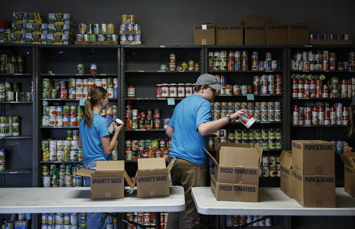 Student volunteers Preston Woodbury, right, and Esther Burton stock newly donated food at the S ...