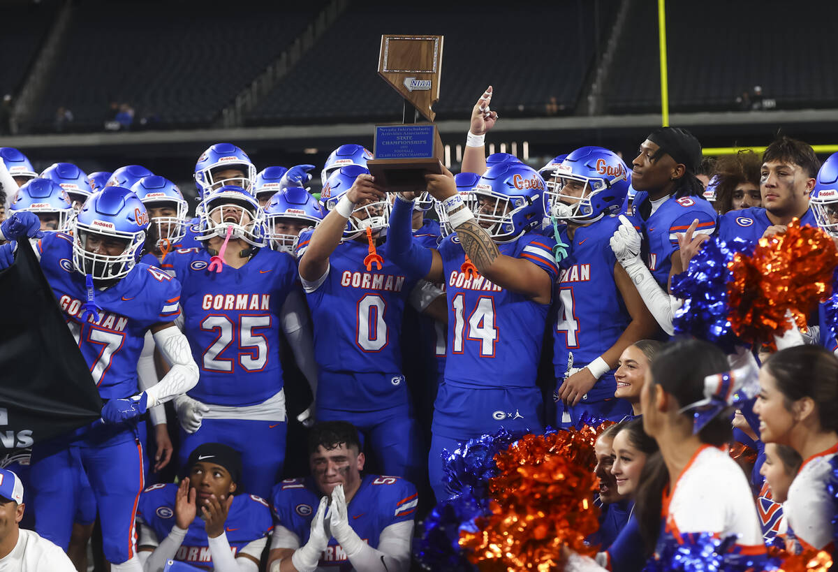 Bishop Gorman players pose for photos with the trophy after defeating Arbor View to win the Ope ...