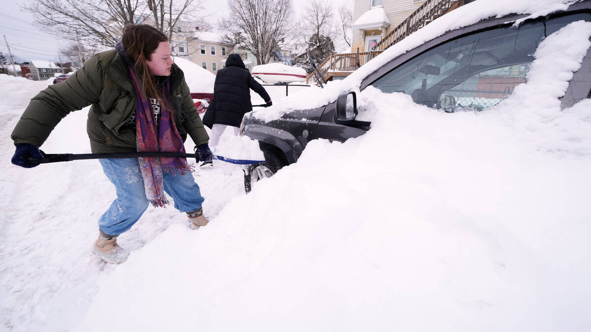 Emma Teske shovels out her car following a winter storm that dumped more than a foot and a half ...