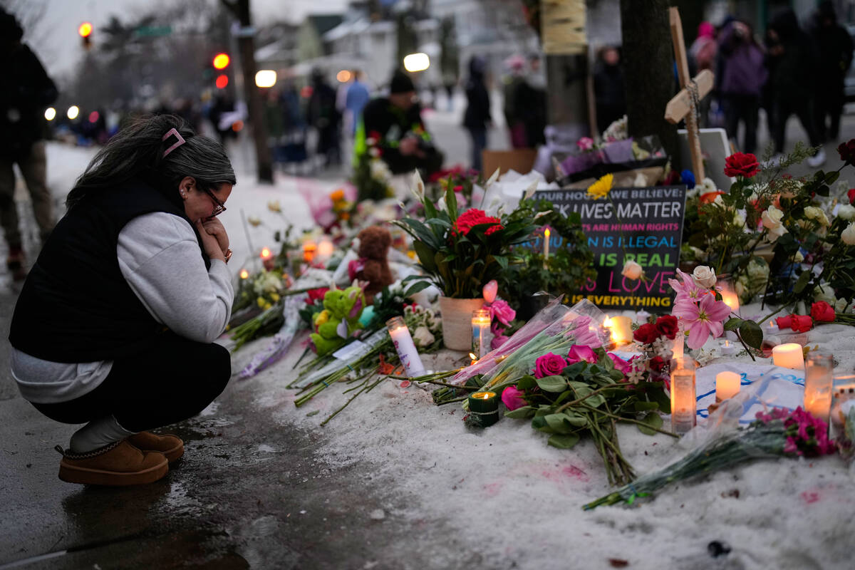A woman gets emotional around a makeshift memorial honoring Renee Good, who was fatally shot by ...