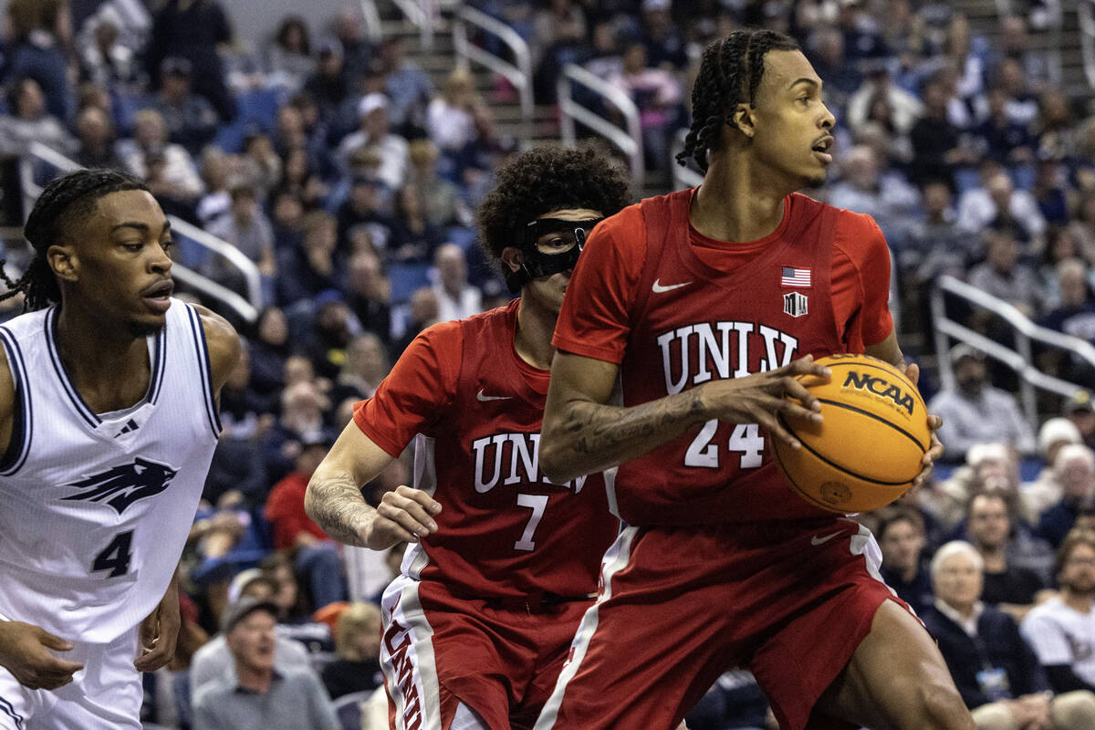 UNLV forward Naas Cunningham (24) looks to pass the ball while being defended by UNR guard Core ...
