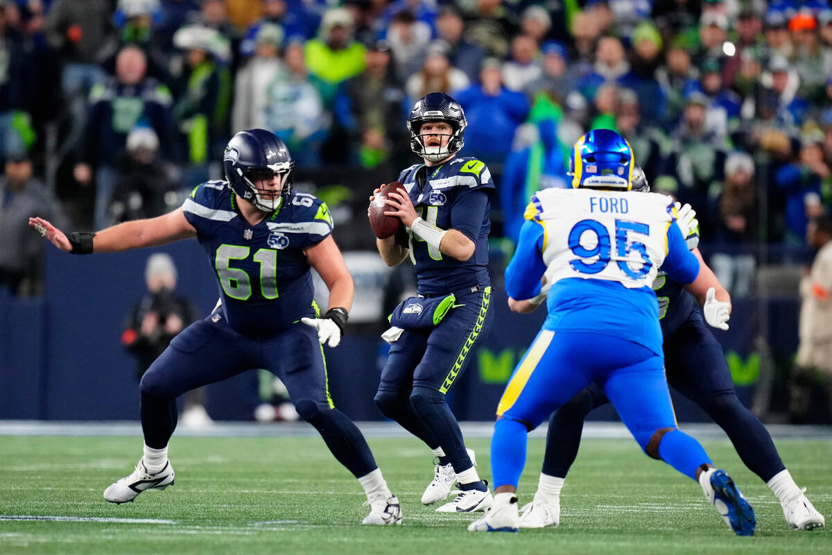 Seattle Seahawks quarterback Sam Darnold (14) looks to pass the ball behind center Jalen Sundel ...