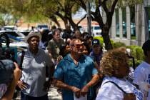 An overflow crowd waits in line in the heat to make a comment during a general consumer session ...