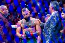 Conor McGregor is consoled by Bruce Buffer in the octagon receiving an injured leg after a quic ...
